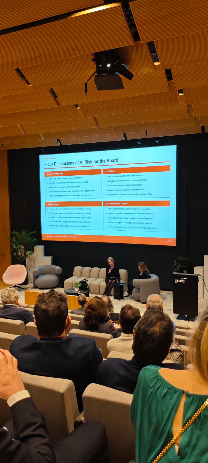 Katia Ciesielska in conversation on stage at PwC NED Day, her slide Four Dimensions of AI Risk for the Board projected behind